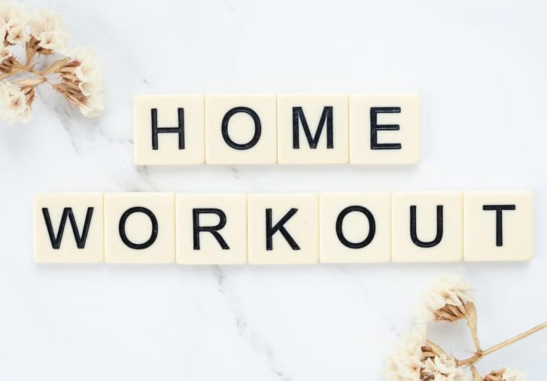 Stylish letter tiles spelling 'Home Workout' on a clean marble background with floral accents.